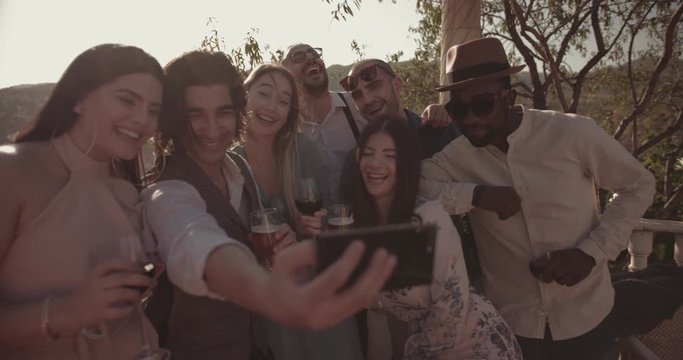Multi-ethnic friends celebrating and taking selfies at traditional mountain house