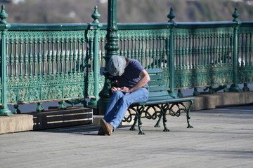 A man cuts his fingernails on a bench nearby the harbor of Quebec-Canada
