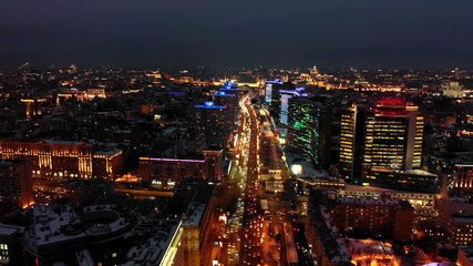 Fototapeta na wymiar Bright lights of night Moscow from bird's eye view. Intensive traffic at New Arbat street in the heart of the city. Illuminated multistory houses on the sides of the wide avenue.