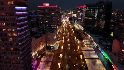 Bright lights of night Moscow from bird's eye view. Intensive traffic at New Arbat street in the heart of the city. Multistory houses illuminated with neon lights on the sides of the wide avenue.