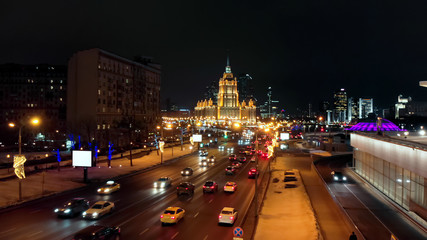 The illuminated Hotel "Ukraine" and intensive traffic on the city streets. Cityscape and the night lights on the New Arbat street and Kutuzovski avenue.