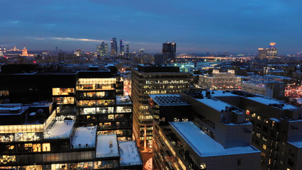 Obraz premium Moscow White square modern business center. Winter evening smooth aerial shot. Open-space offices through the illuminated windows.