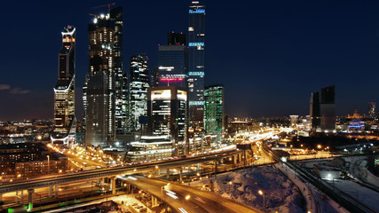 Fototapeta na wymiar Moscow-city night life Beautiful shot. City traffic and night illumination. Skyscrapers with illuminated windows in the middle of traffic junction.