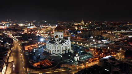 Flying around the Cathedral of Christ the Savior in Moscow. Bright lights of night city life. River Moskva and city panorama at night.