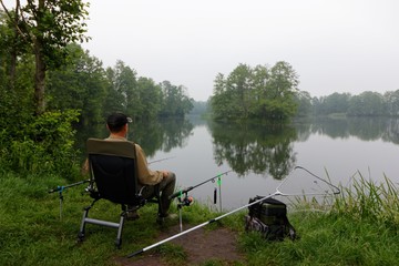 Fisherman sitting on the chair and fishing during cloudy day