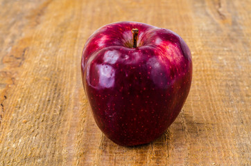 Single red ripe sweet apple with green leaves