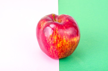 Single red ripe sweet apple with green leaves
