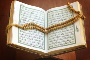 rosary and holy quran book on wood stand