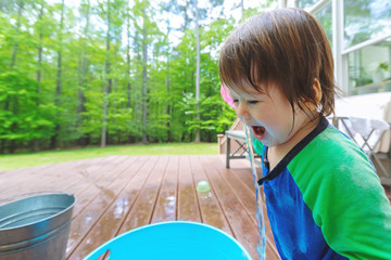 Young toddler boy playing with water outside