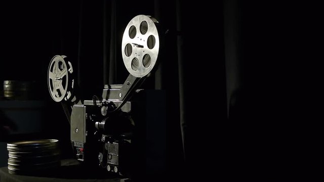 The old film projector plays in a dark room.