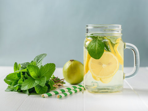 Fresh drink of lemon, lime, mint and ginger with two cocktail tubes on a white table.