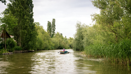 Beautiful river landscape with a small fishing boat going along the river