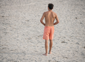 unknown teen walks the beach alone thinking about his future