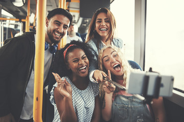 Laughing group of friends taking selfies together on the bus