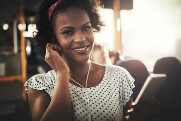Smiling young African woman listening to music during her commute