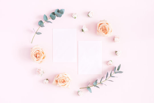 Flowers composition. Paper blank, rose flowers, eucalyptus branches on pastel pink background. Flat lay, top view, copy space