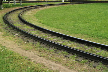 View of tramway curved rails with green grass.