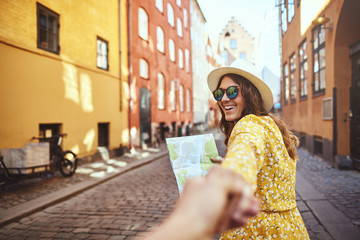 Smiling woman holding a map leading someone through the city