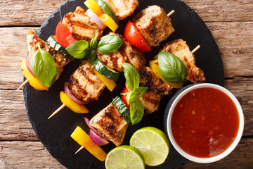 grilled chicken skewers with summer vegetables with sauce, basil and lime closeup. horizontal top view