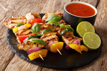 Hot grilled chicken kebab skewers with colorful vegetables with sauce, basil and lime closeup. horizontal