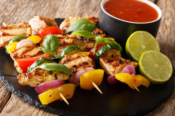 grilled chicken skewers with summer vegetables with sauce, basil and lime closeup. horizontal