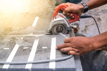 Close up of worker making cut sandstone by electric hand stone saws, working with power tools