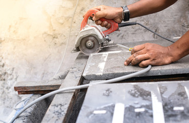 Close up of worker making cut sandstone by electric hand stone saws, working with power tools