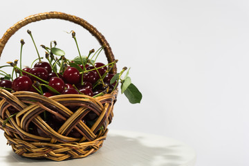Fototapeta na wymiar Fresh cherry in bascketl on a white wooden table
