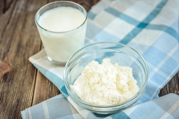 Cottage cheese and glass of milk with pear blossom on dark wooden background.
