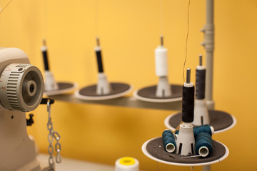 string of black and white threads on white sewing machine on yellow wall