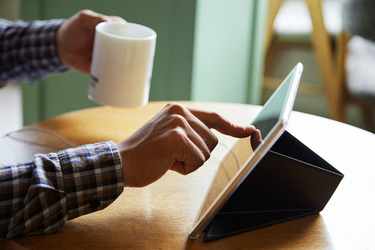 Close-up of man touching his tablet at the table at cafe