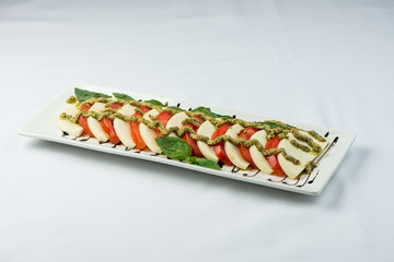 tomatoes coarsely chopped with cheese, on a square plate on a white background . Cold snack