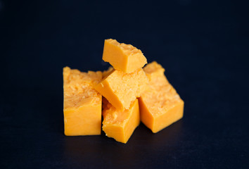 Tasty gouda or parmesan aged cheese in pieces on the black background, horizontal photo. Food and delicatesse concept.