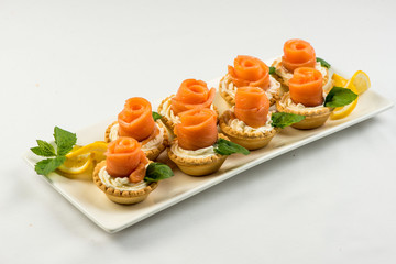The salted smoked salmon in the basket is made in the form of a rose on a white plate