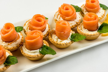 The salted smoked salmon in the basket is made in the form of a rose on a white plate