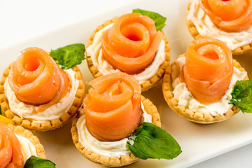 The salted smoked salmon in the basket is made in the form of a rose on a white plate