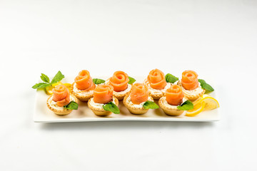 The salted smoked salmon in the basket is made in the form of a rose on a white plate