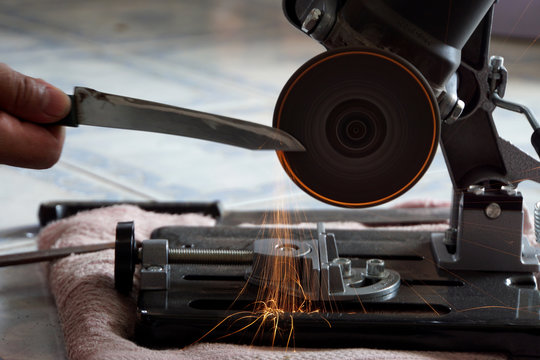 Knife sharpening, blured small knife with equibment machanic working have fire sparkle.