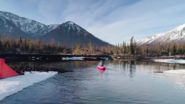 aerial. tourist sailing on a rubber boat in lake near camping in mountain valley