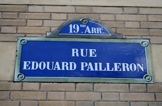 Rue Edouard Pailleron. Plaque de nom de rue sur mur de briques jaunes.