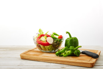 Full bowl of fresh salad on a white wooden