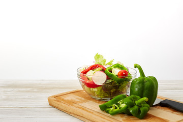 Full bowl of fresh salad on a white wooden