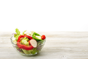 Full bowl of fresh salad on a white wooden