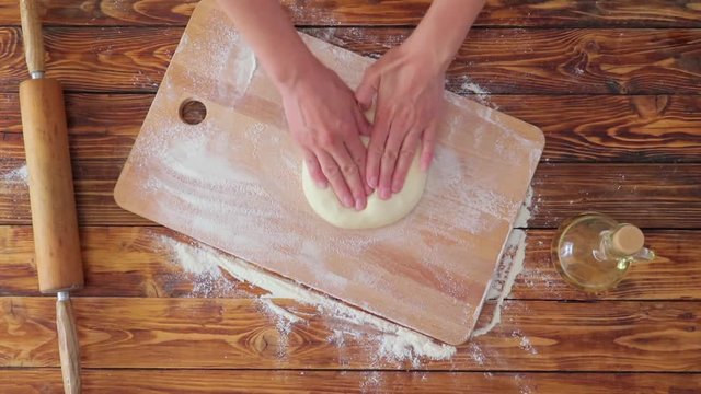 Woman's hands make dough on wooden board, top view video