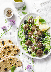 Greek lamb meatballs with avocado greek yogurt sauce, couscous and whole grain flatbread on a light background, top view. Mediterranean style food