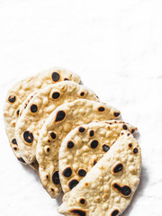 Homemade whole grain tortillas on a light background, top view