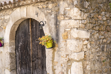 old wintage wood door in france with flowers in a wall of stones from a very old house