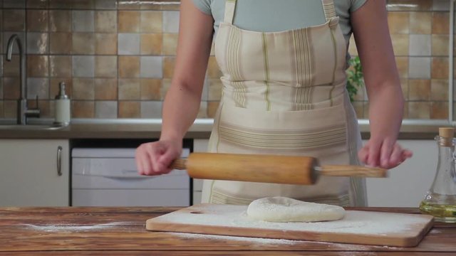 Woman rolling pizza dough on the kitchen, slow motion video