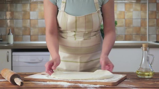 Woman rolling pizza dough using rolling pin. Woman doing homemade pizza.