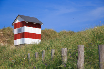 red and white beach cabin on danish seaside